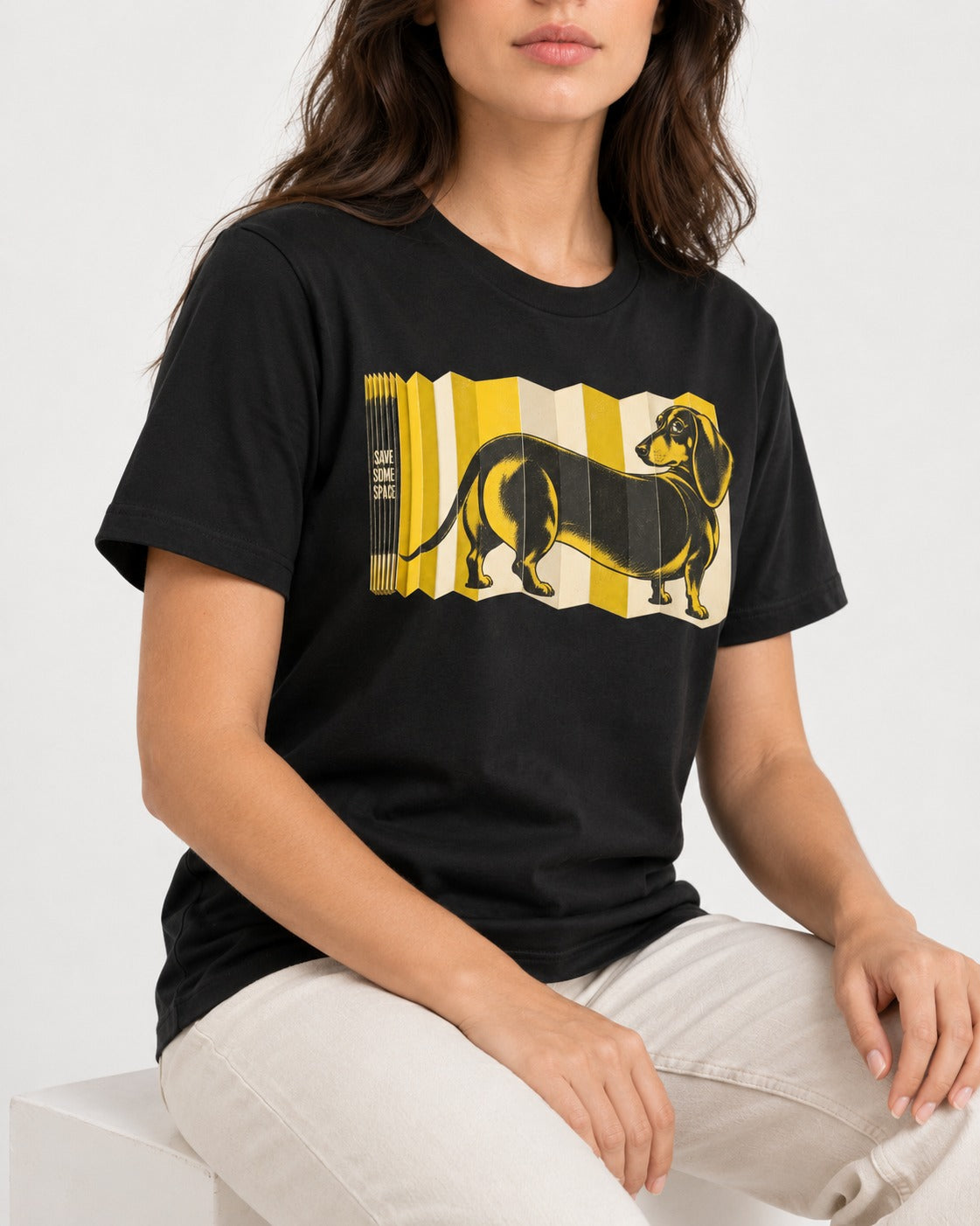Dachshund Save Some Space Accordion Screen Graphic T-Shirt in Black, worn by a seated model