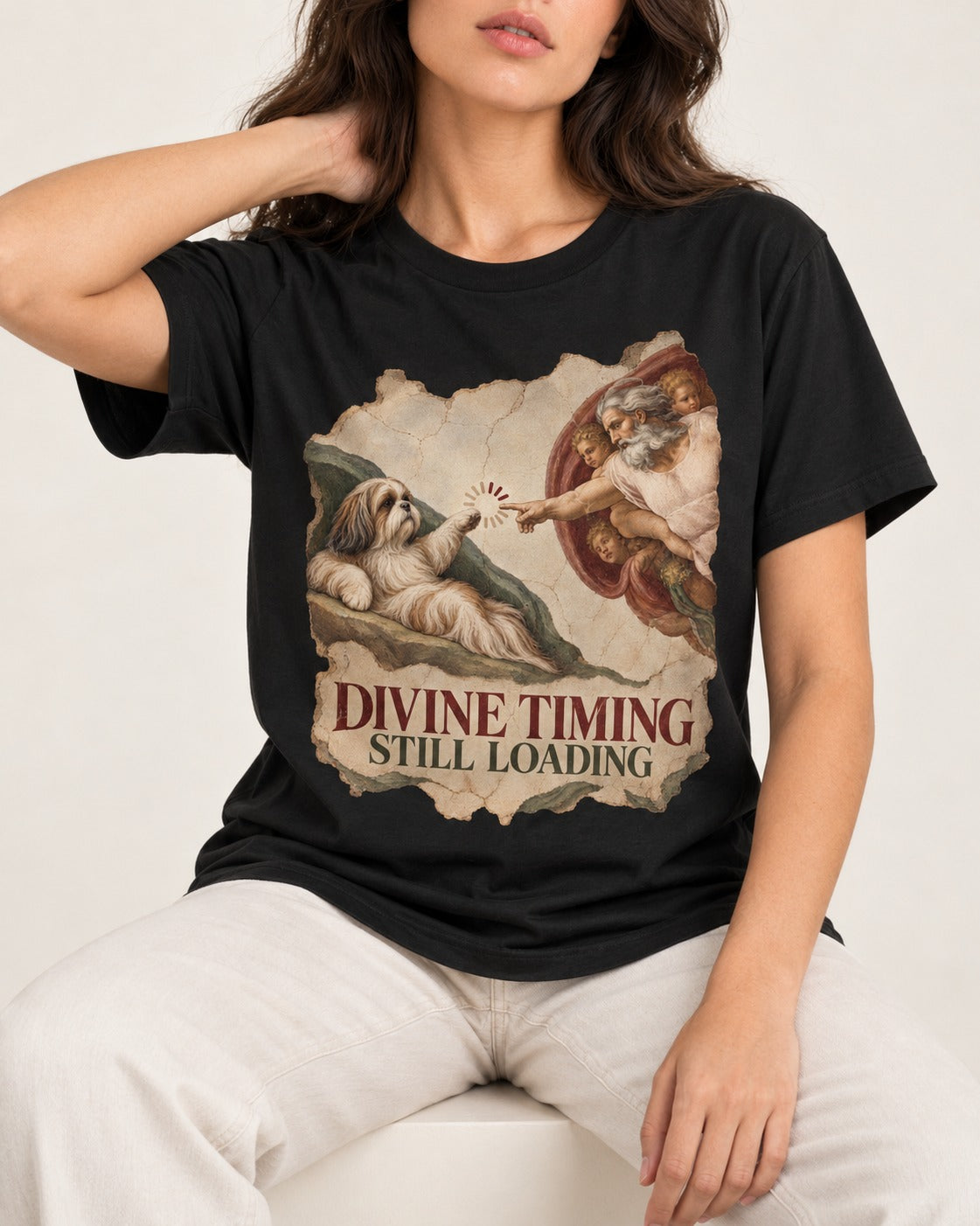Shih Tzu Divine Timing Still Loading Renaissance Parody Graphic T-Shirt in Black, worn by a seated model