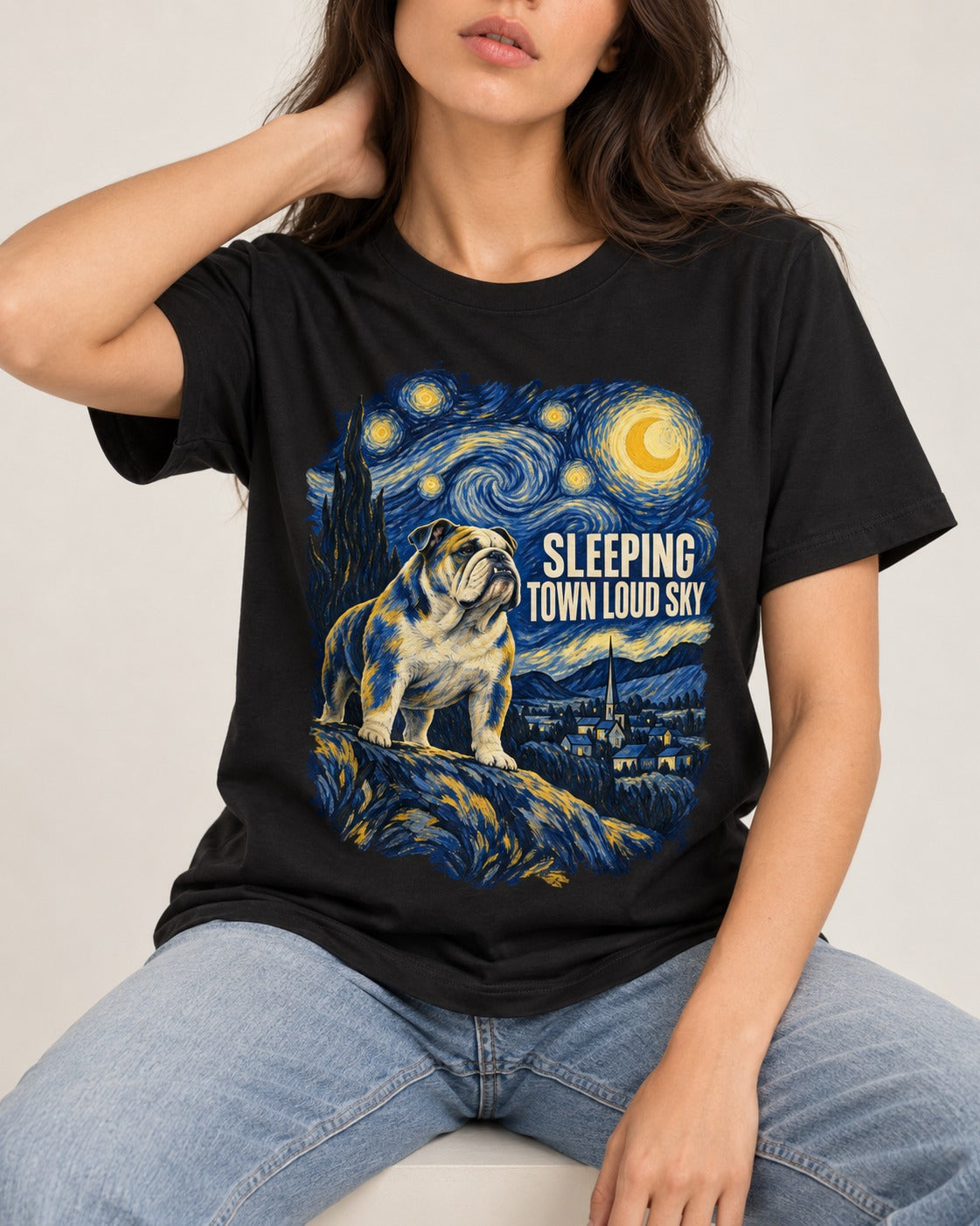 English Bulldog Sleeping Town Loud Sky Starry Night Graphic T-Shirt in Black, worn by a seated model