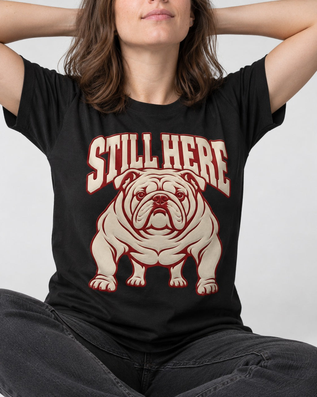 English Bulldog Still Here Collegiate Graphic T-Shirt in Black, worn by a seated model