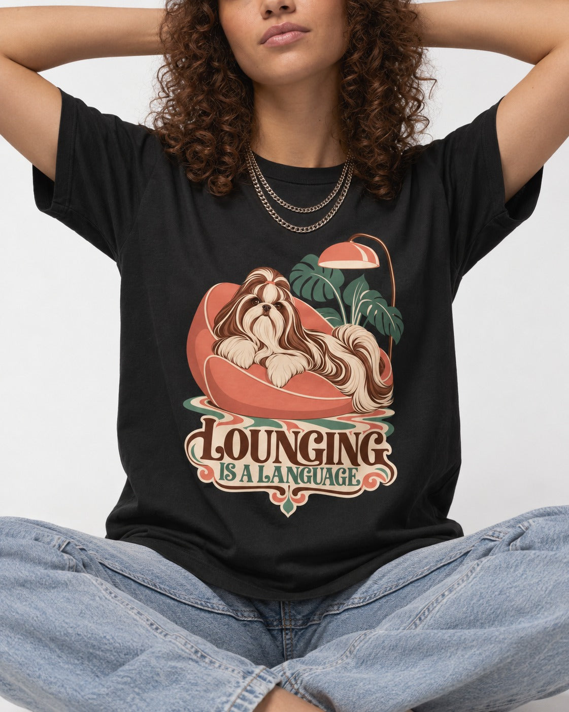 Shih Tzu Lounging Is a Language Retro Lounge Graphic T-Shirt in Black, worn by a seated model