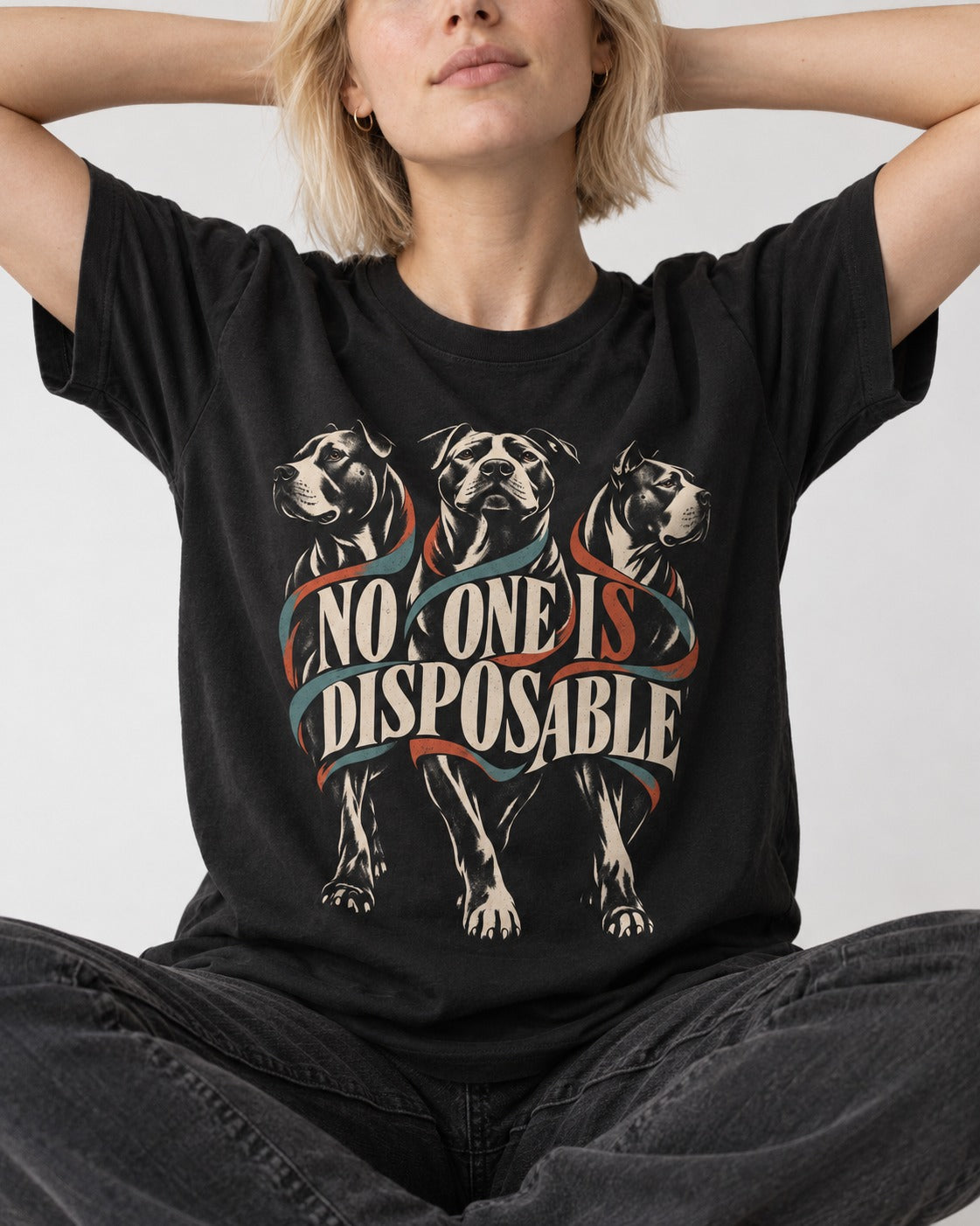 Pitbull No One Is Disposable Three Dogs Graphic T-Shirt in Black, worn by a seated model