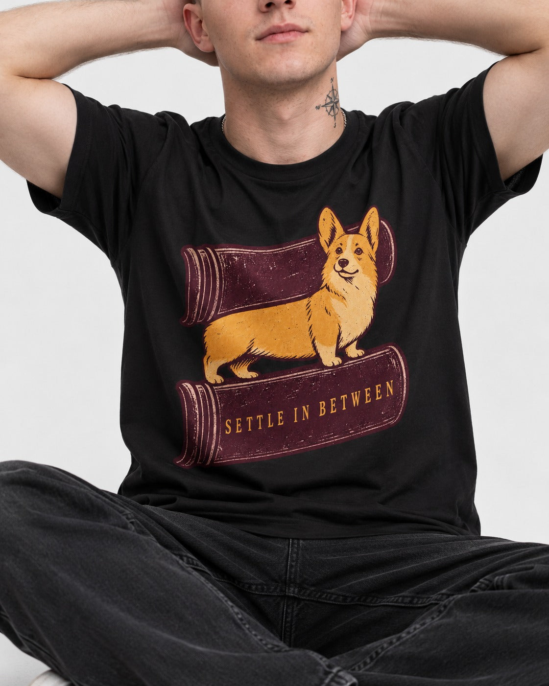 Corgi Settle in Between T-Shirt in Black, worn by a seated model