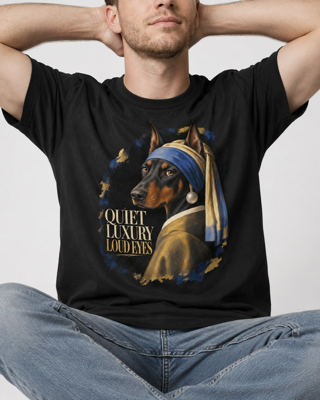 Doberman Quiet Luxury Loud Eyes Pearl Portrait Graphic T-Shirt in Black, worn by a seated model