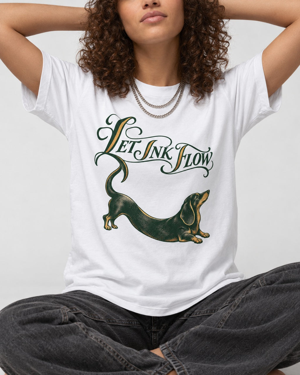 Let the Dachshund Ink Flow T-Shirt in White, worn by a seated model