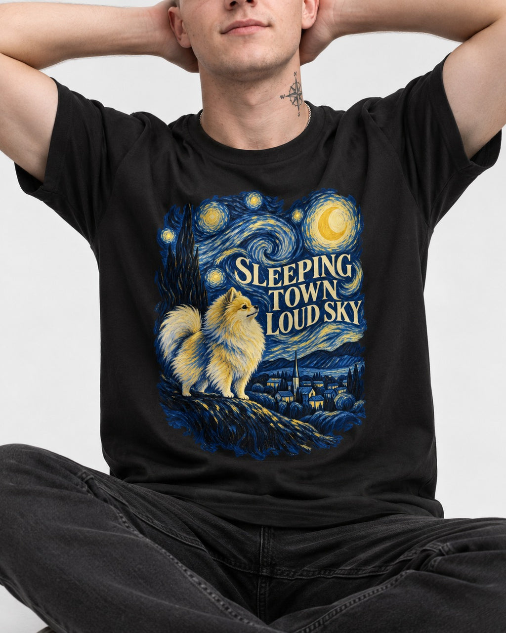 Pomeranian Sleeping Town Loud Sky Starry Night Graphic T-Shirt in Black, worn by a seated model