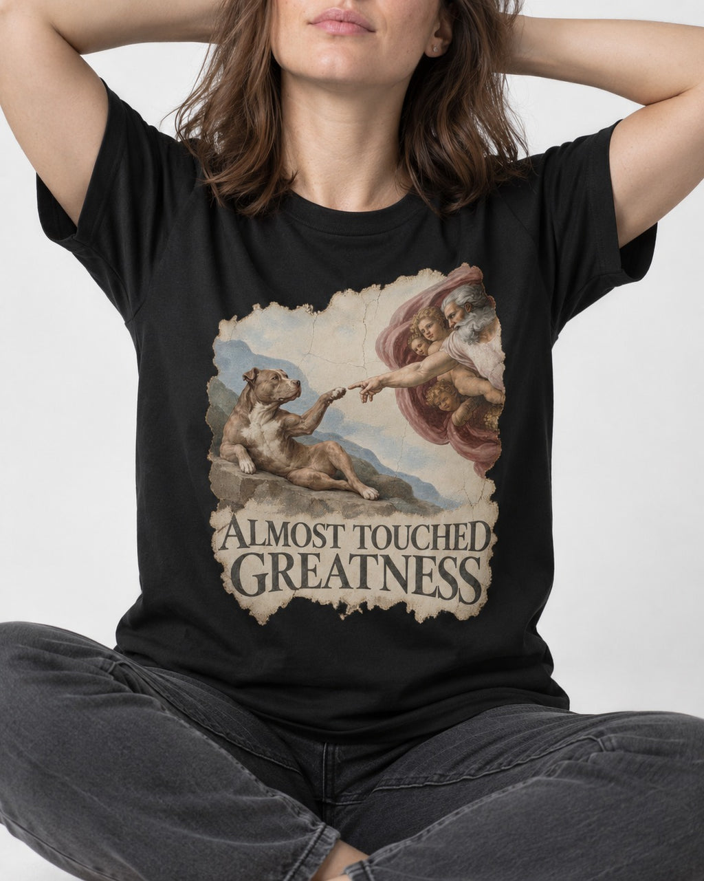 Pitbull Almost Touched Greatness Creation Parody Graphic T-Shirt in Black, worn by a seated model