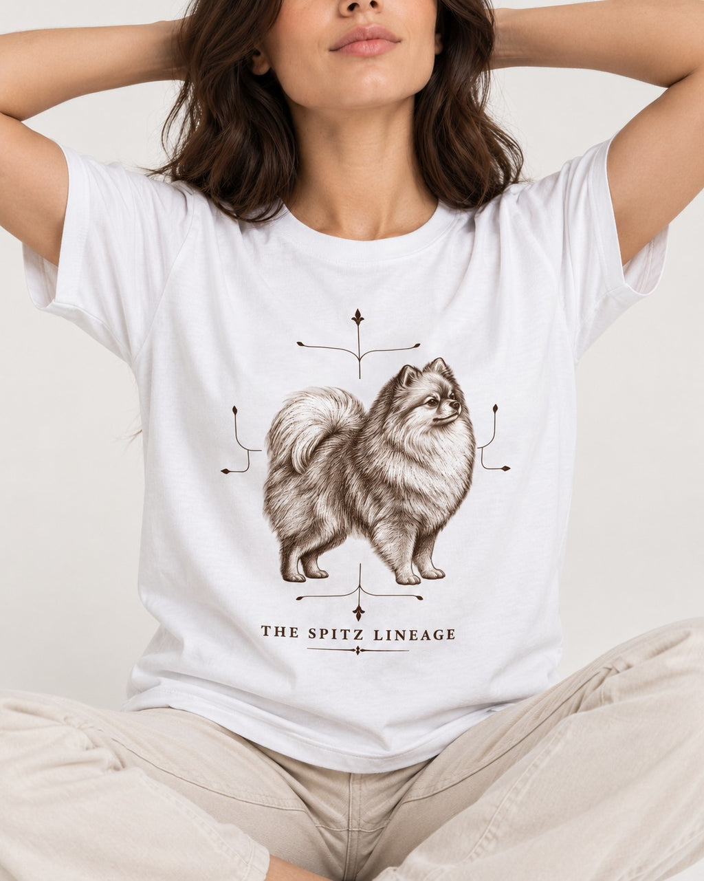 Pomeranian Spitz Lineage T-Shirt in White, worn by a seated model