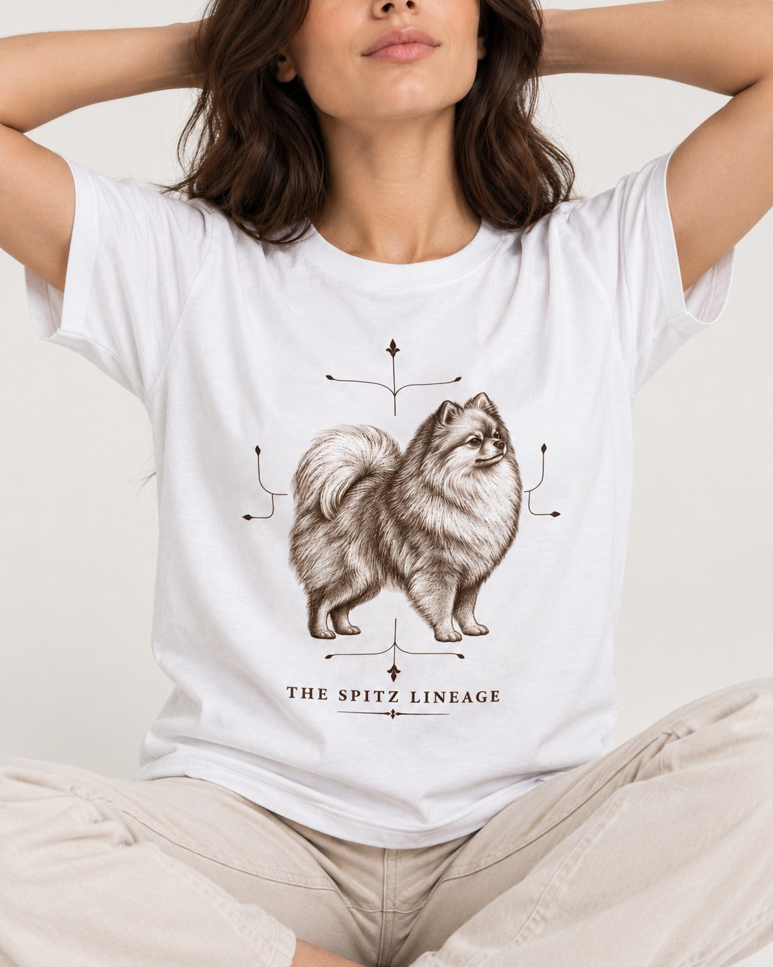 Pomeranian Spitz Lineage T-Shirt in White, worn by a seated model