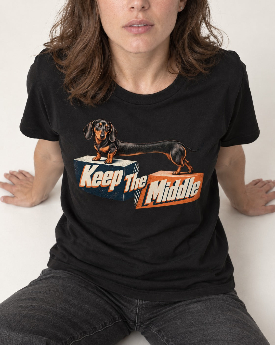 Dachshund Keep The Middle Block Bridge Graphic T-Shirt in Black, worn by a seated model