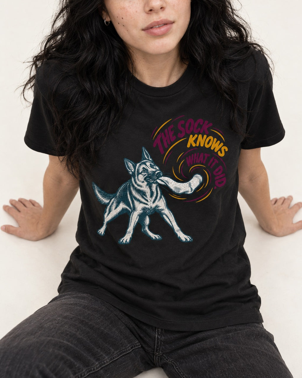 German Shepherd Dog The Sock Knows What I Did Graphic T-Shirt in Black, worn by a seated model