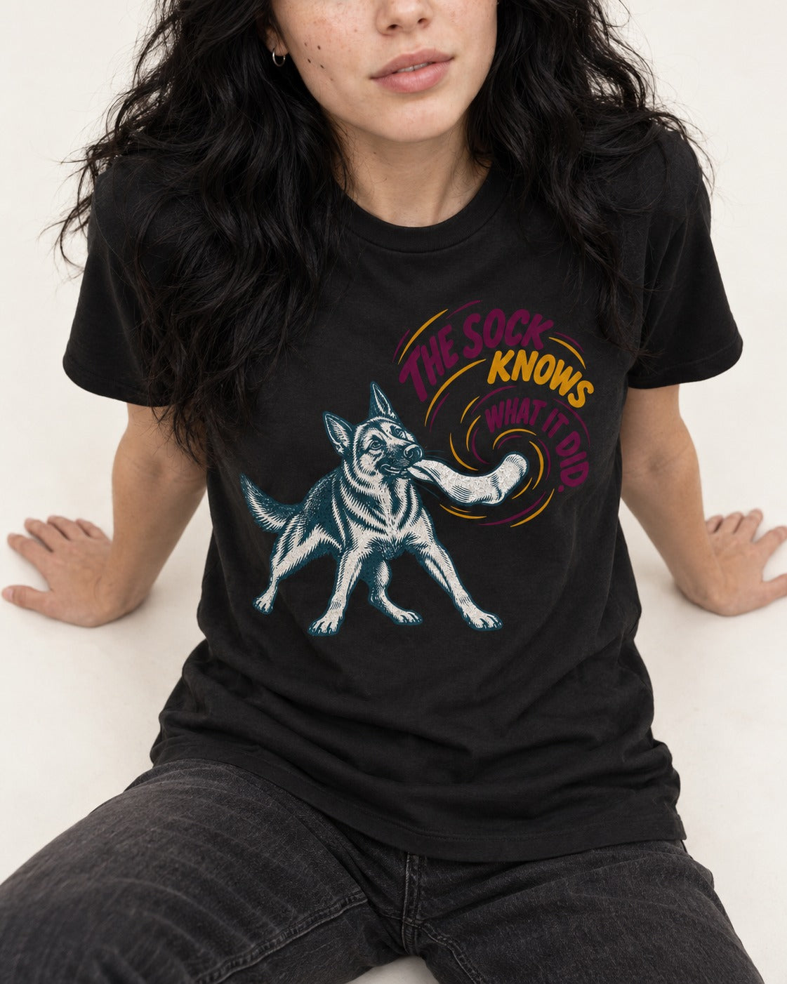 German Shepherd Dog The Sock Knows What I Did Graphic T-Shirt in Black, worn by a seated model