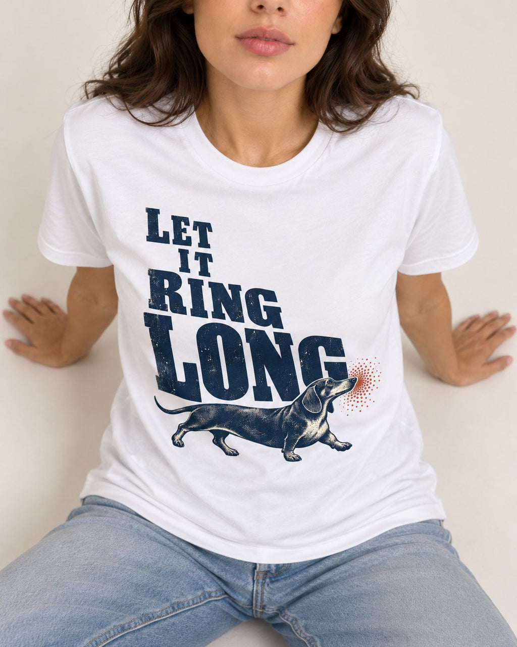 Let It Ring Long Dachshund T-Shirt in White, worn by a seated model