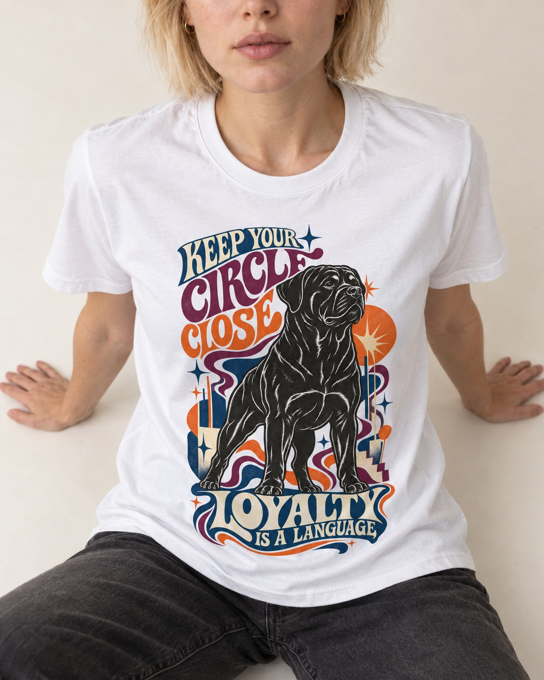 Keep Your Rottweiler Circle Close T-Shirt in White, worn by a seated model