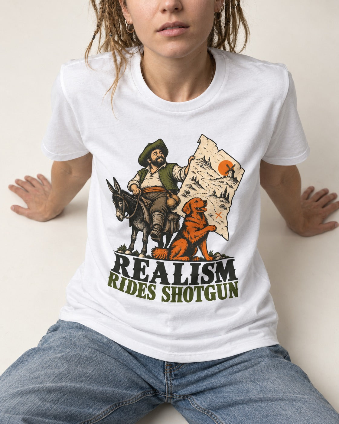 Realism Rides Shotgun with Golden Retriever T-Shirt in White, worn by a seated model