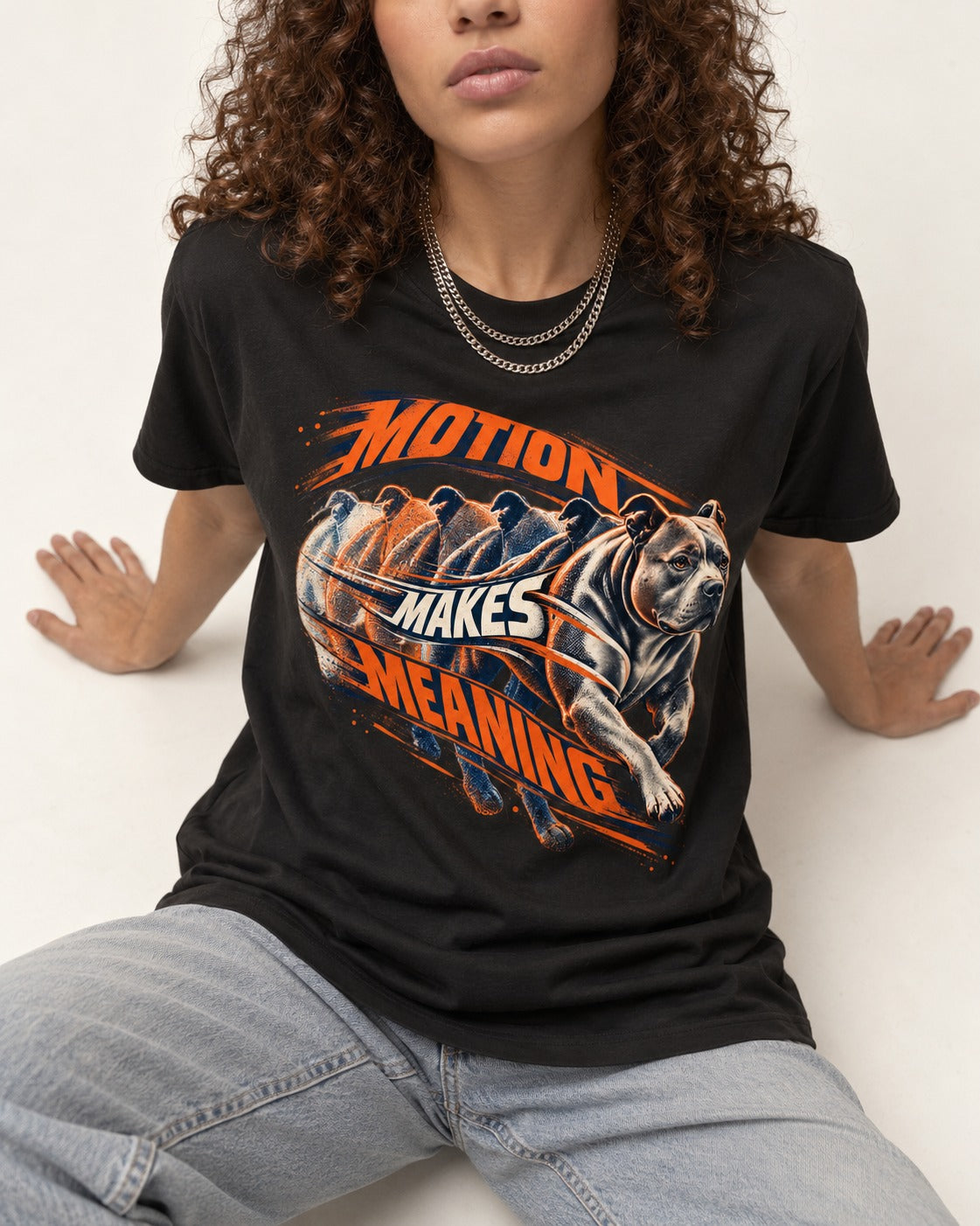 Pitbull Motion Makes Meaning Running Dog Graphic T-Shirt in Black, worn by a seated model