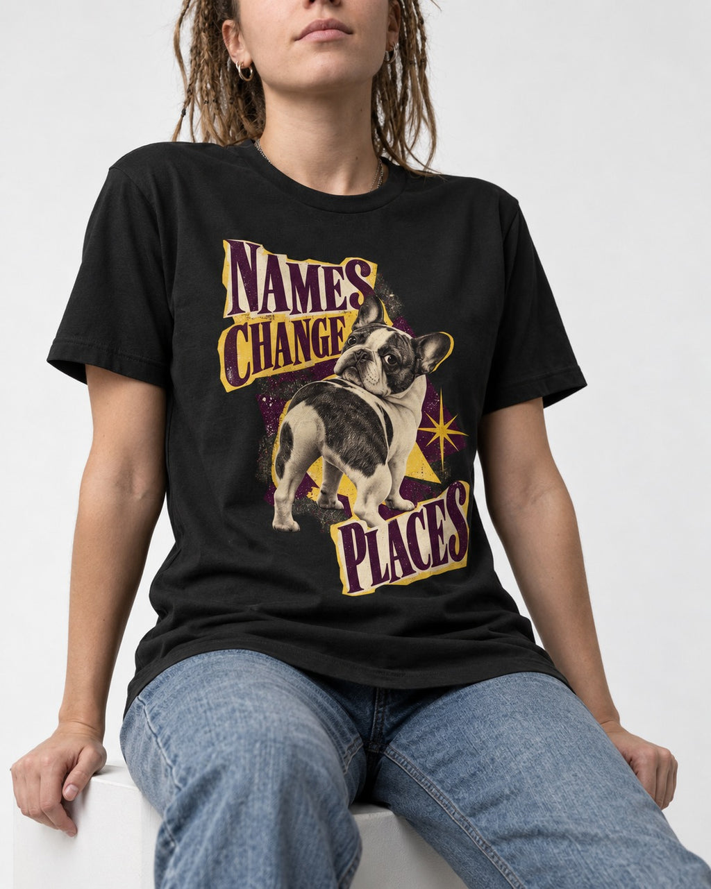 Frenchie Names Change Places Purple Poster Graphic T-Shirt in Black, worn by a seated model