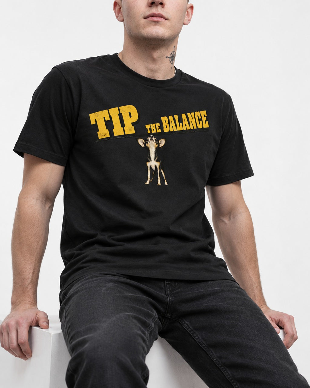 Chihuahua Tip the Balance Beam Graphic T-Shirt in Black, worn by a seated model