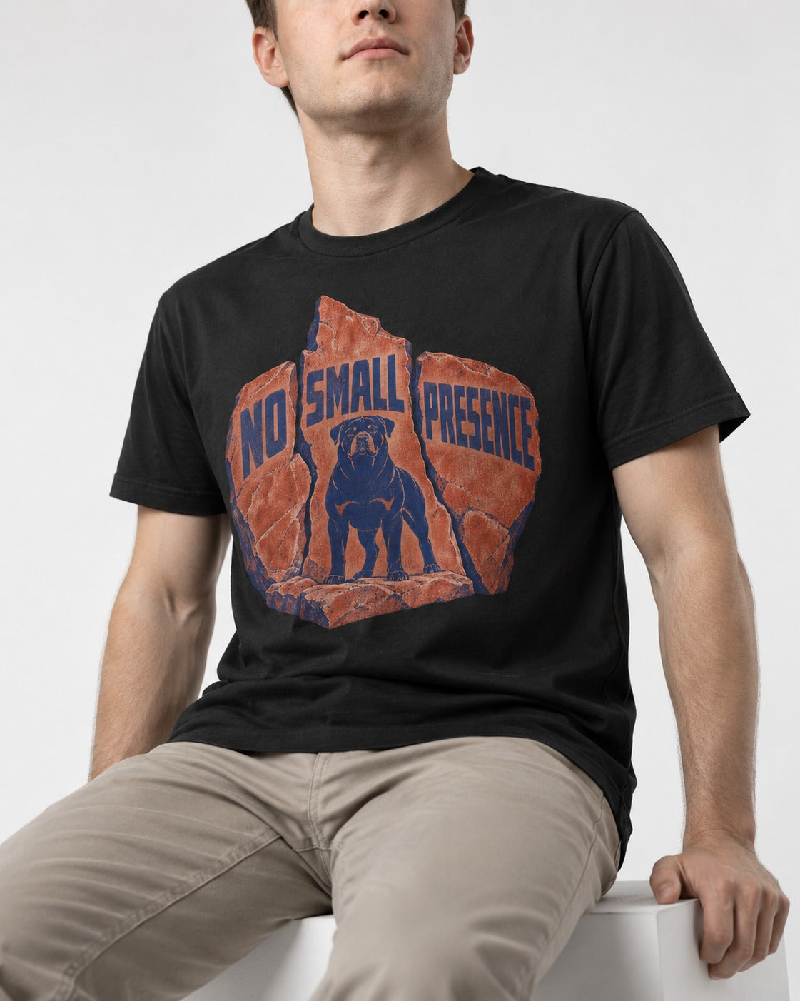 Rottweiler No Small Presence Monument Rock Graphic T-Shirt in Black, worn by a seated model