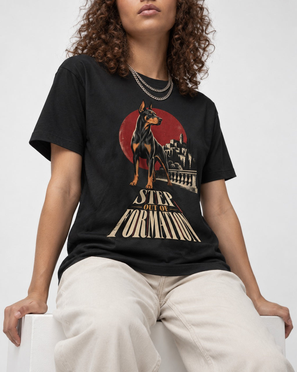Doberman Step Out of Formation Road Vista Graphic T-Shirt in Black, worn by a seated model