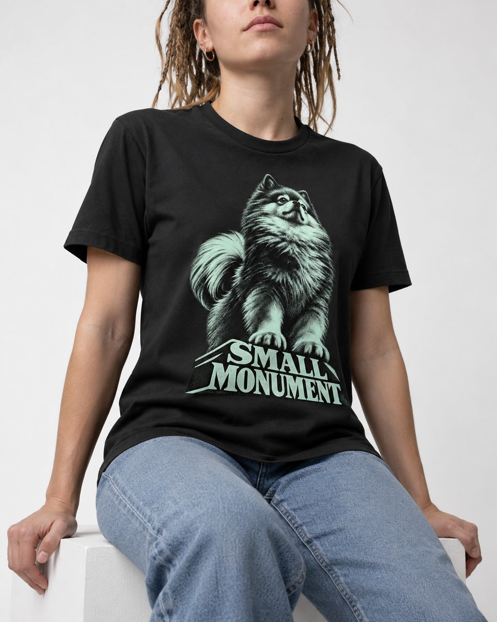 Pomeranian Small Monument Pedestal Graphic T-Shirt in Black, worn by a seated model