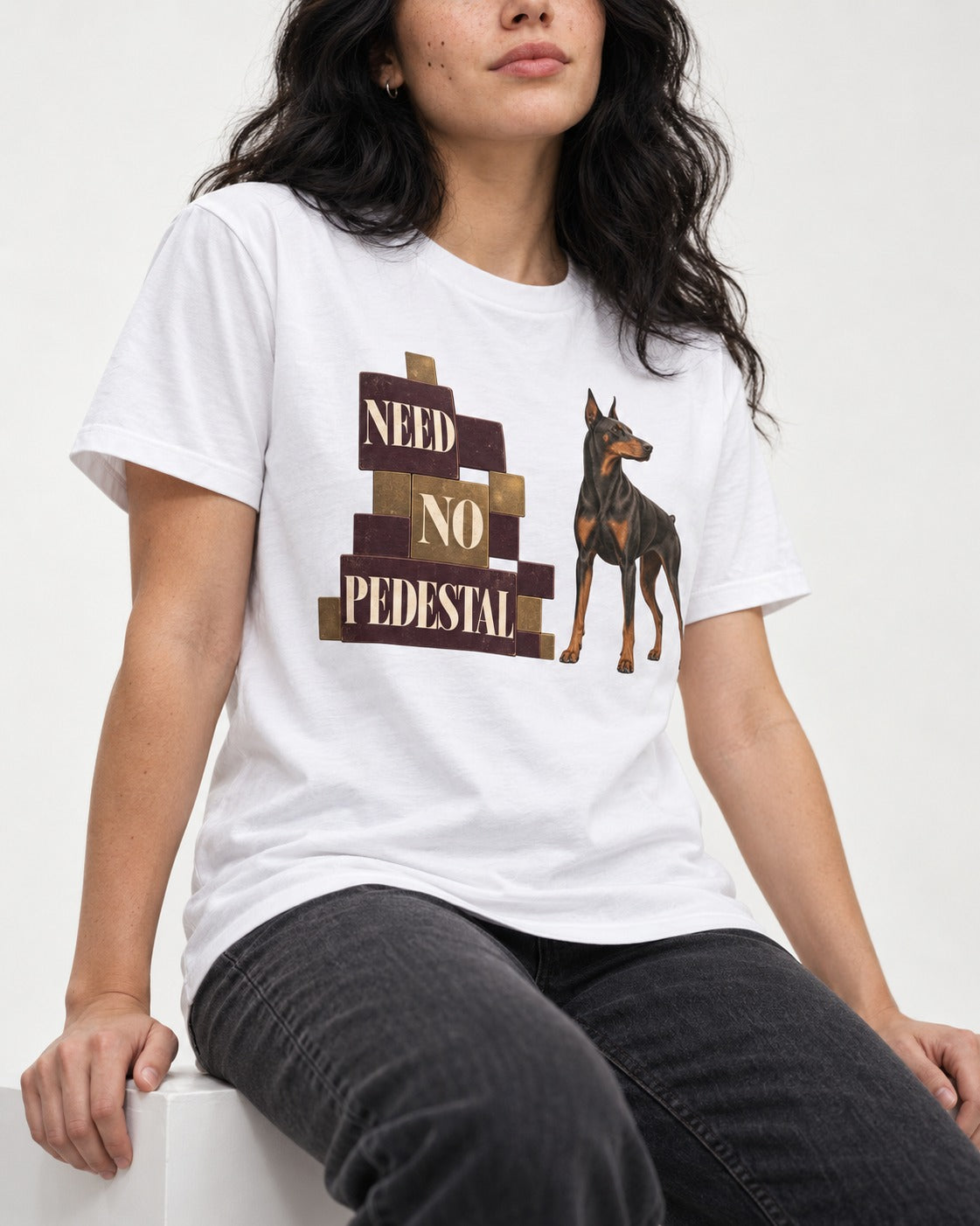 Doberman Need No Pedestal T-Shirt in White, worn by a seated model