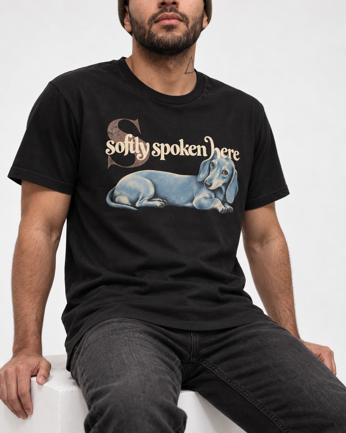 Dachshund Softly Spoken Here Reclining Portrait Graphic T-Shirt in Black, worn by a seated model