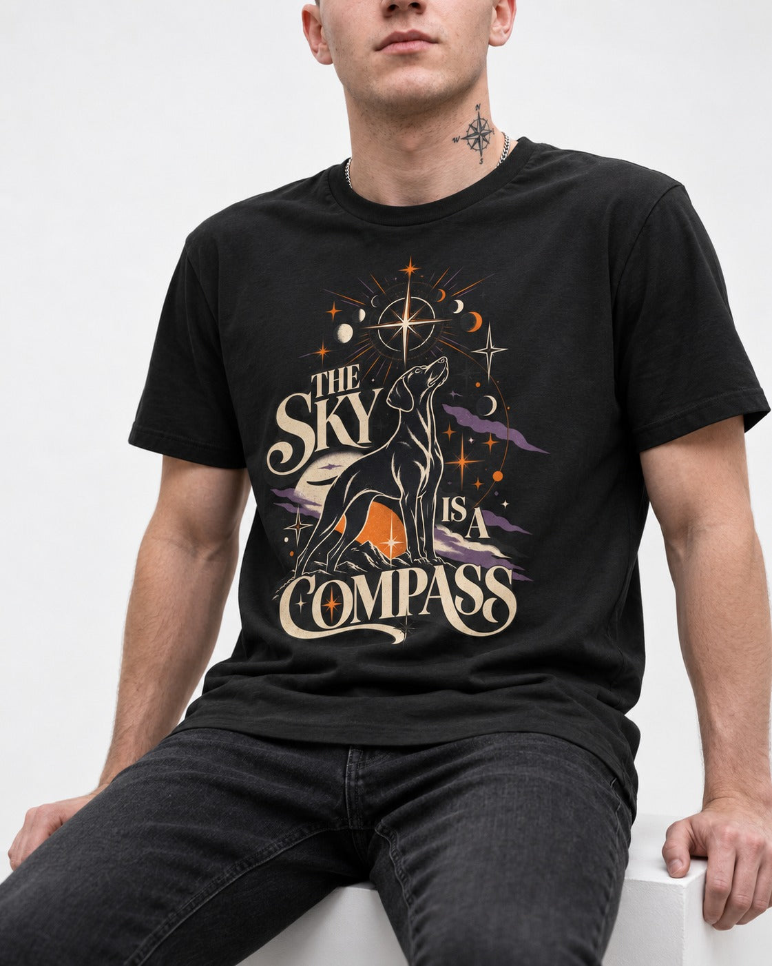 The Sky Is a Compass Celestial German Shorthaired Pointer Graphic T-Shirt in Black, worn by a seated model