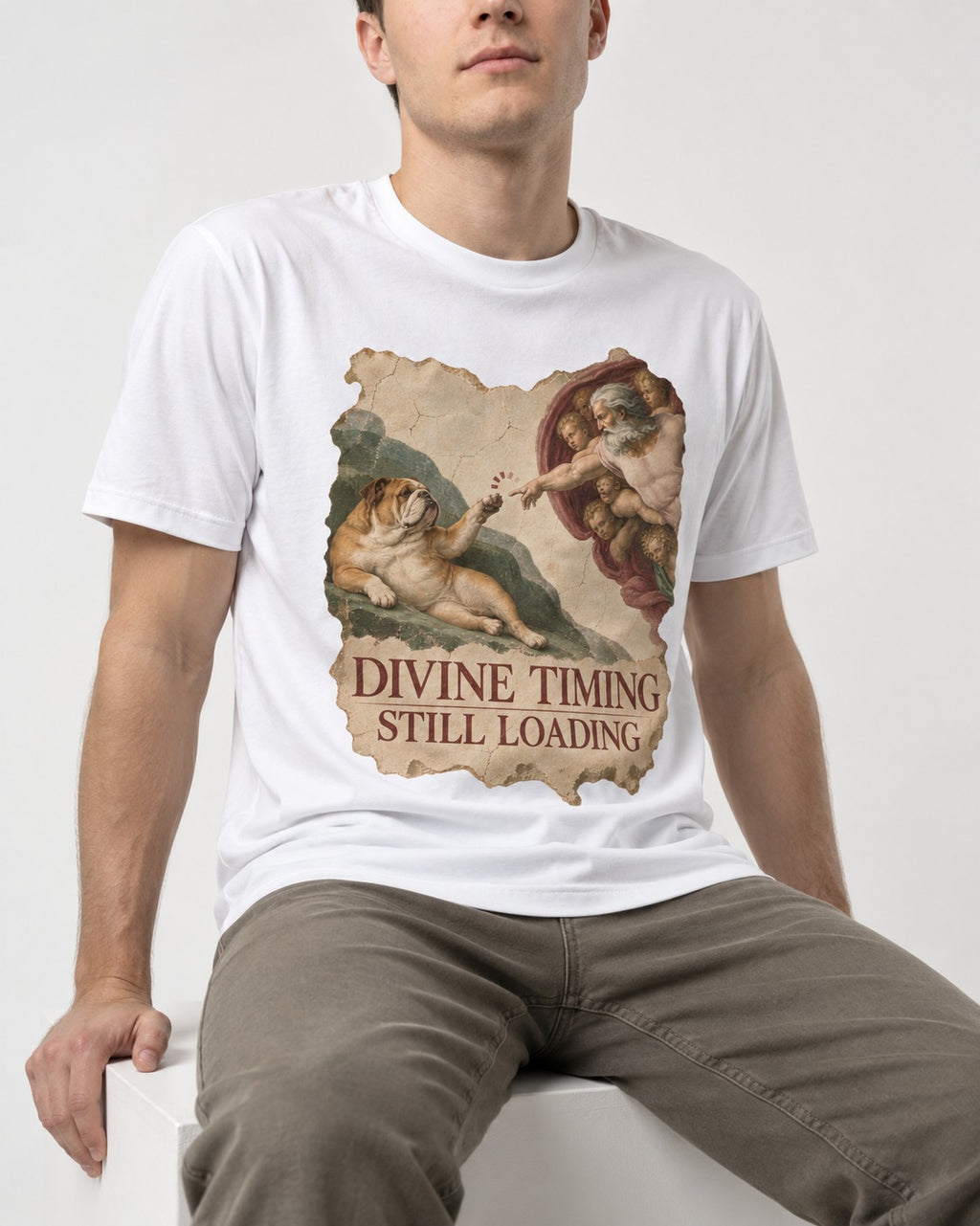 English Bulldog Divine Timing Still Loading T-Shirt in White, worn by a seated model