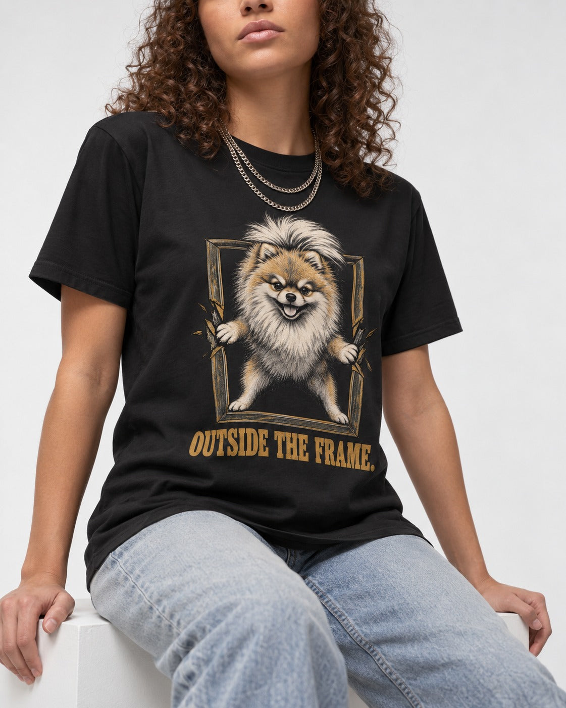 Pomeranian Outside the Frame Breakthrough Graphic T-Shirt in Black, worn by a seated model