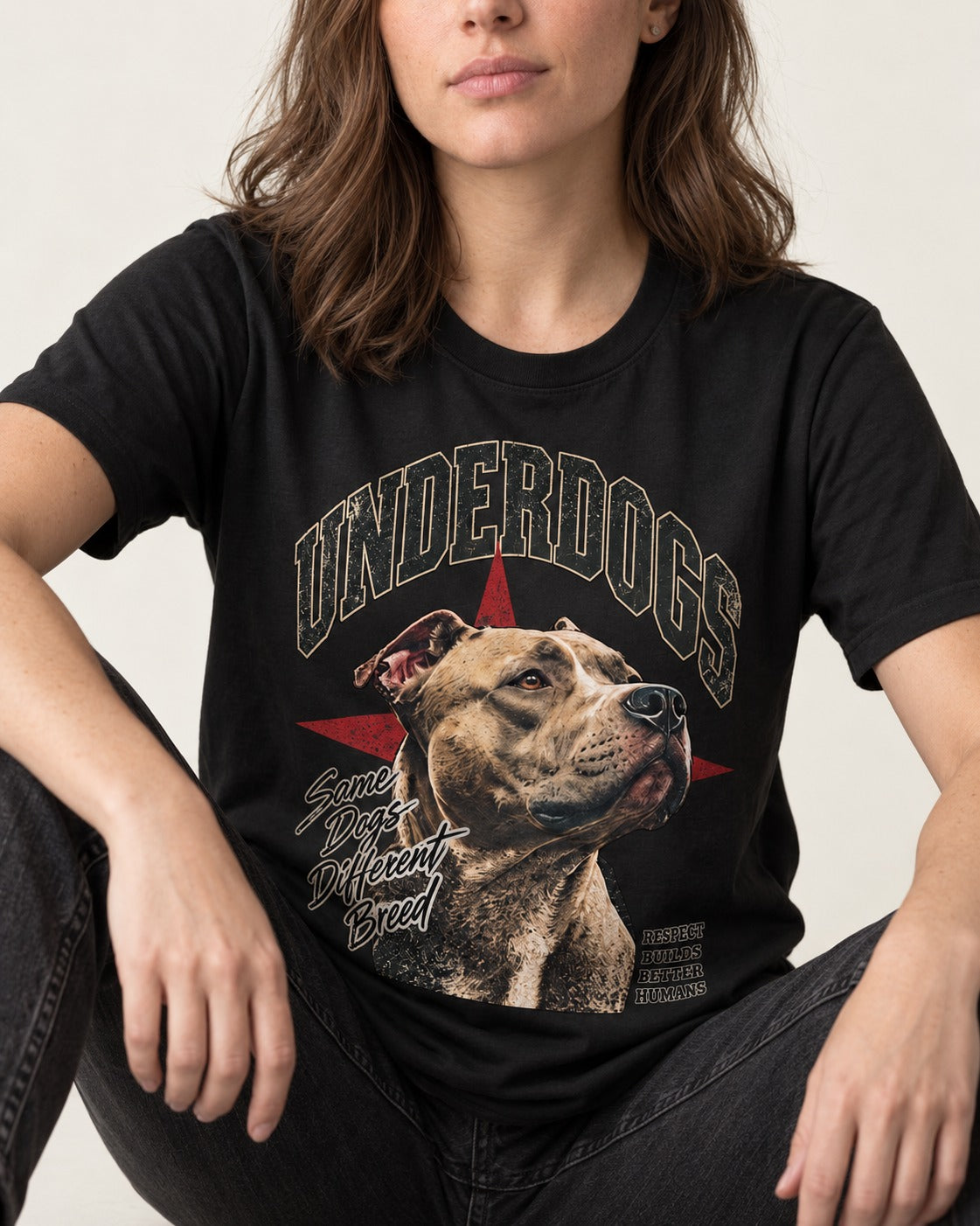 Pitbull Underdogs Same Dogs Different Breed Portrait Graphic T-Shirt in Black, worn by a seated model