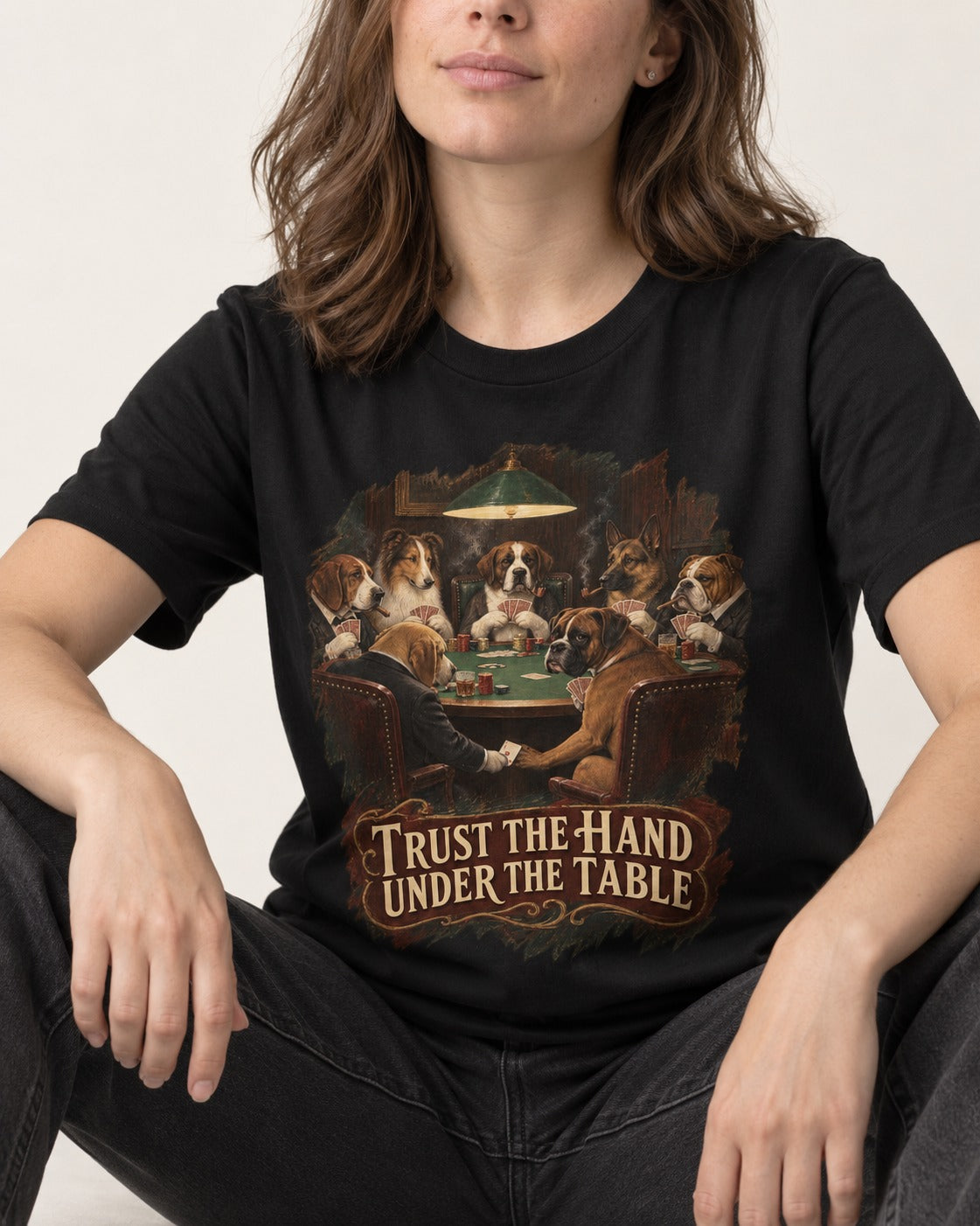 Trust the Hand Under the Table Boxer Poker Graphic T-Shirt in Black, worn by a seated model