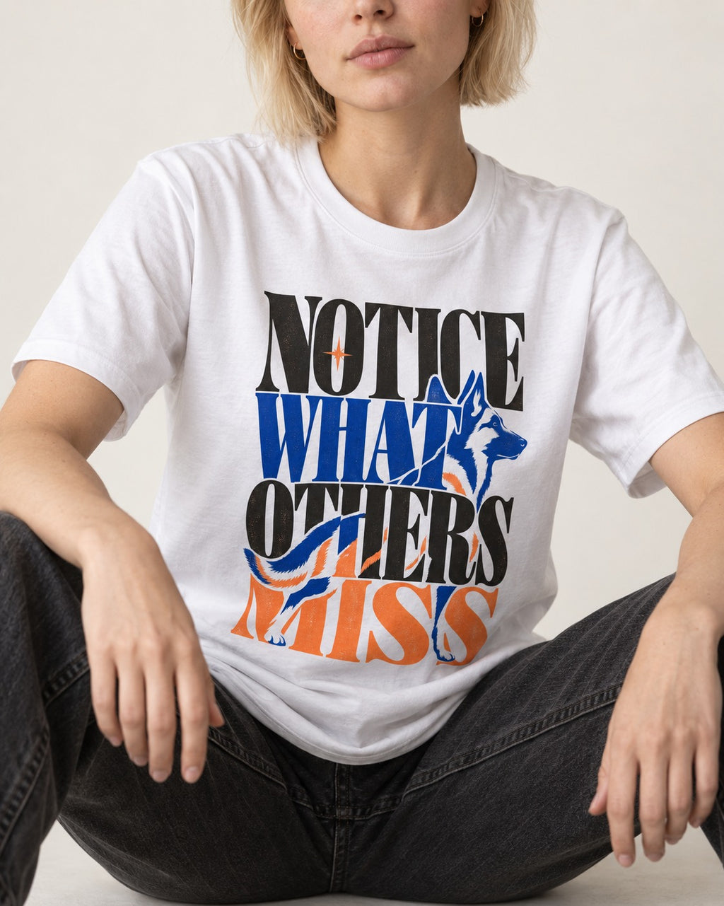Notice What Others Miss German Shepherd Dog T-Shirt in White, worn by a seated model