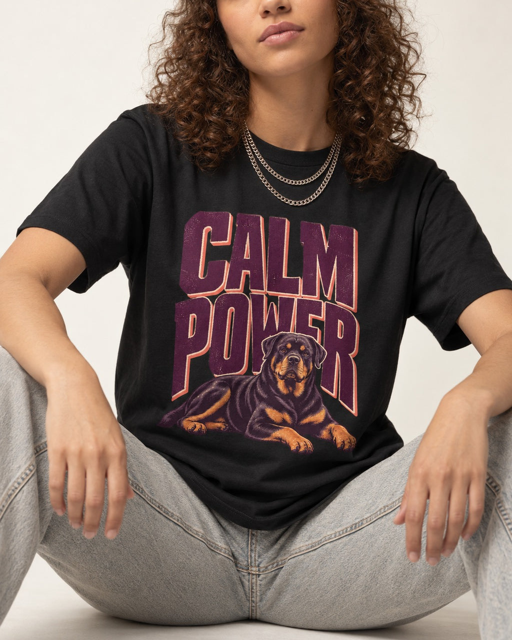 Rottweiler Calm Power Resting Dog Graphic T-Shirt in Black, worn by a seated model