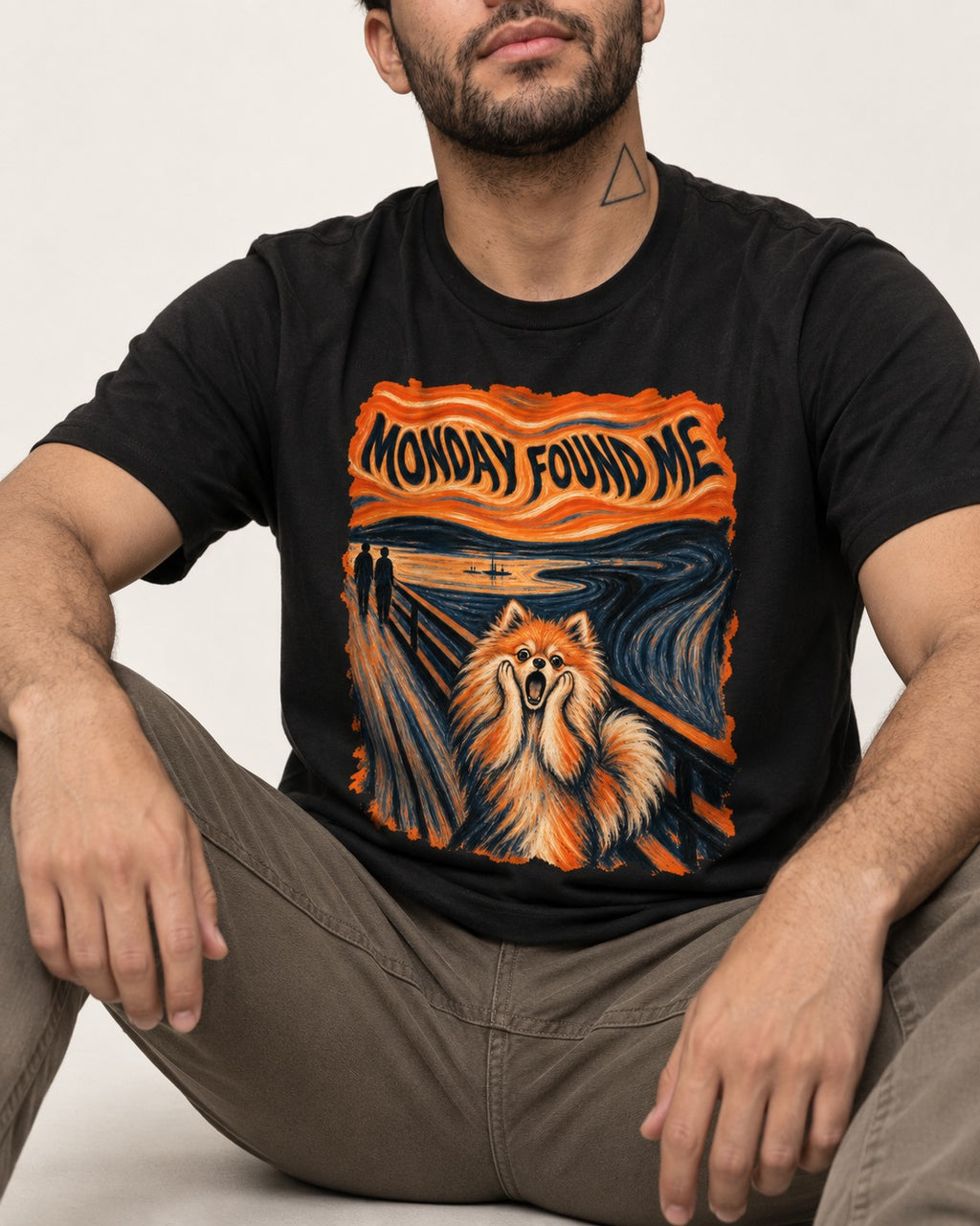 Pomeranian Monday Found Me Scream Parody Graphic T-Shirt in Black, worn by a seated model