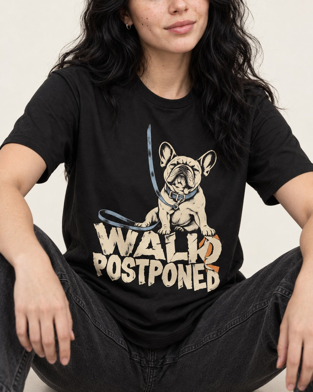 Frenchie Walk Postponed Leash Graphic T-Shirt in Black, worn by a seated model