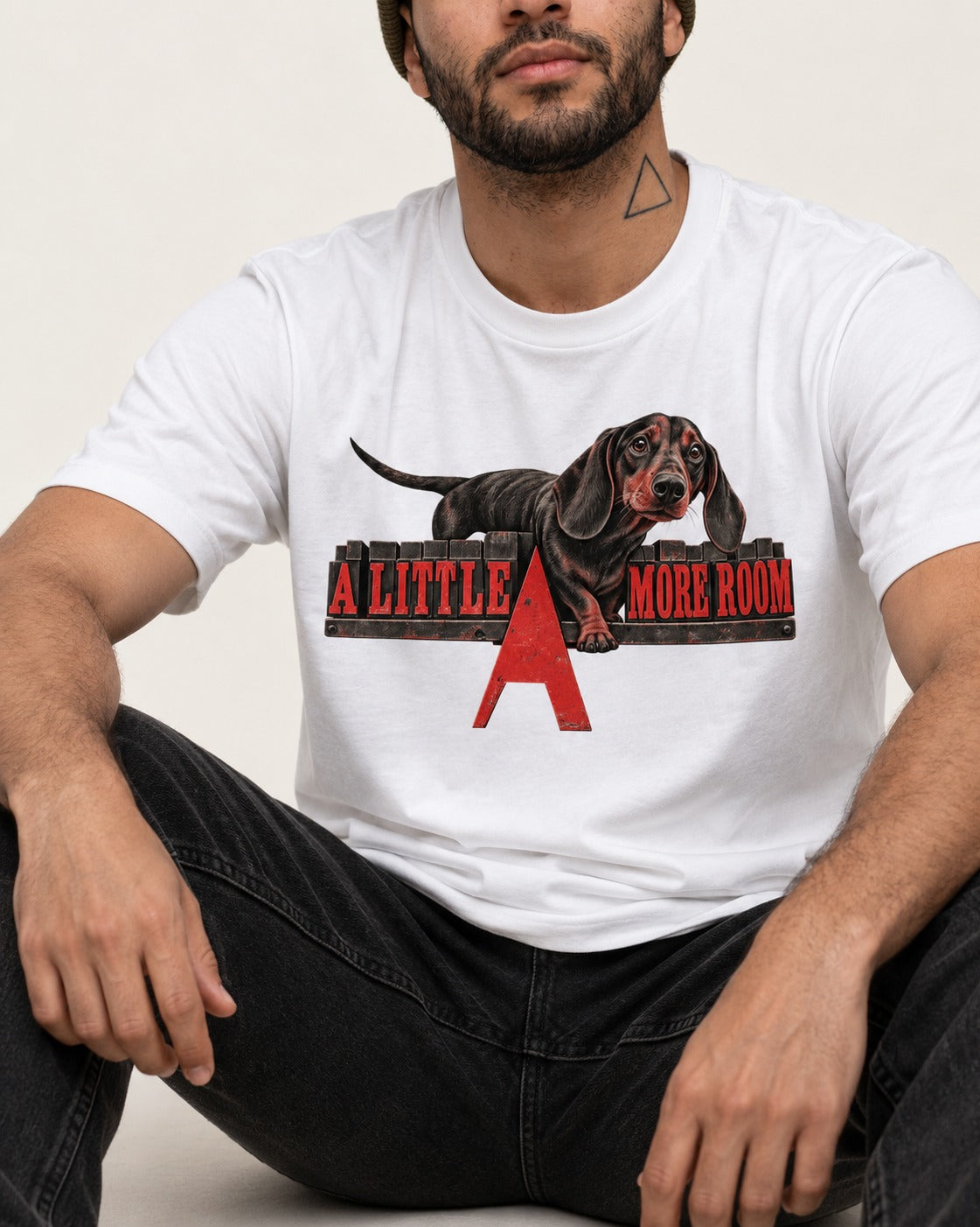 More Room for Dachshund T-Shirt in White, worn by a seated model