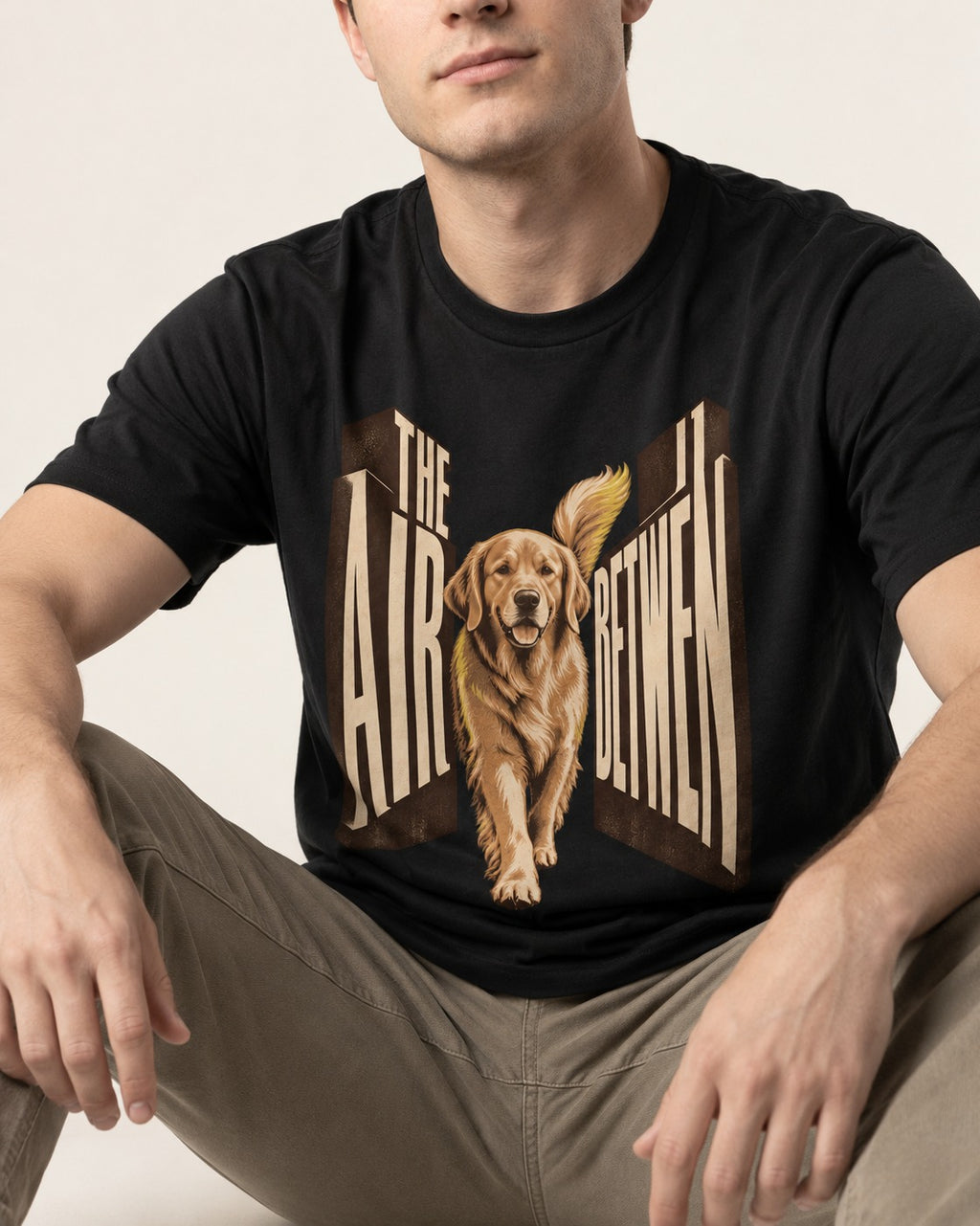 The Air Between Dimensional Golden Retriever Graphic T-Shirt in Black, worn by a seated model