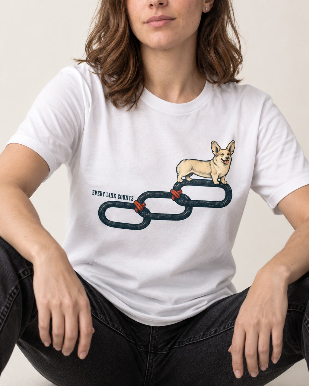 Every Corgi Link Counts T-Shirt in White, worn by a seated model