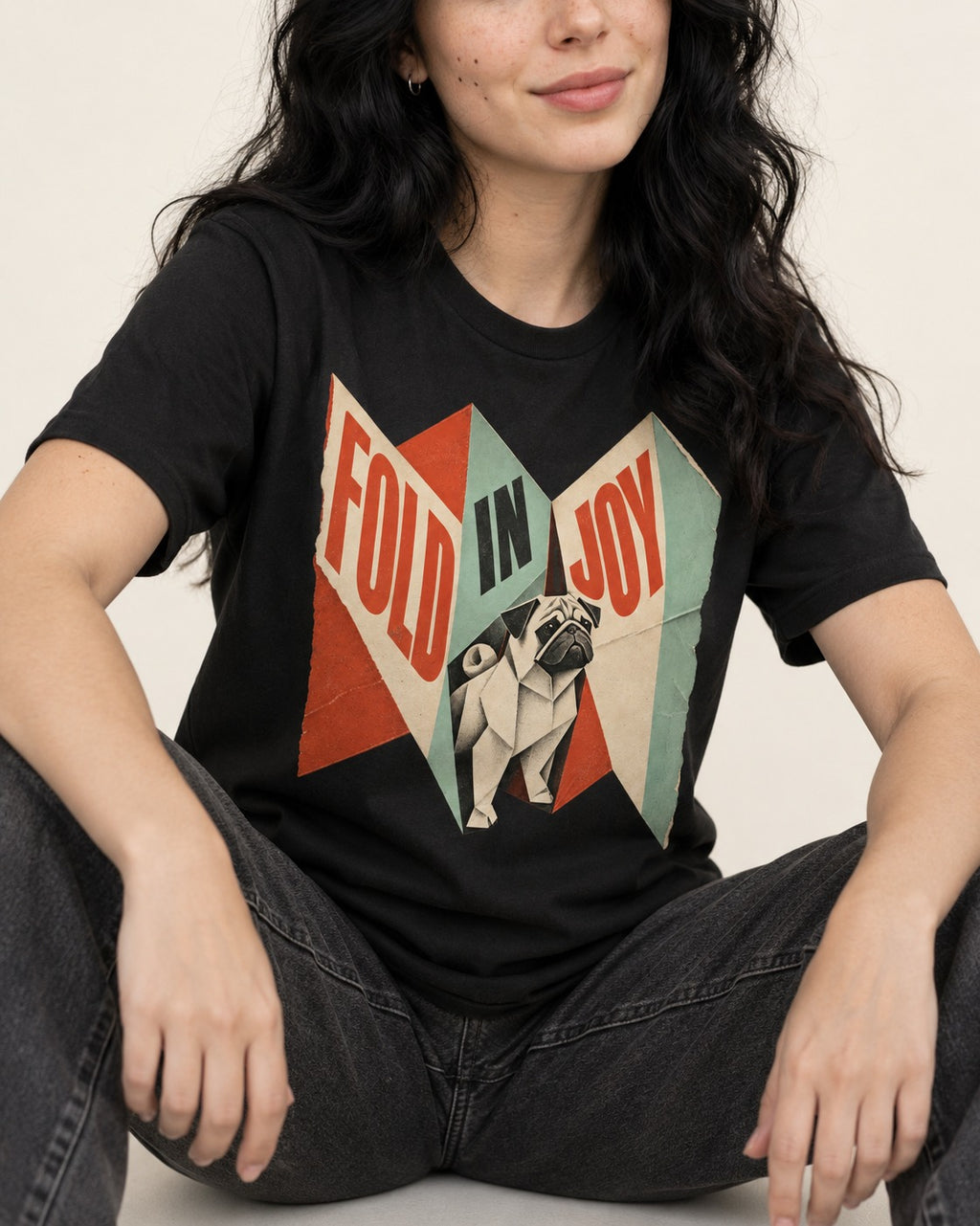 Pug Fold in Joy Geometric Poster Graphic T-Shirt in Black, worn by a seated model