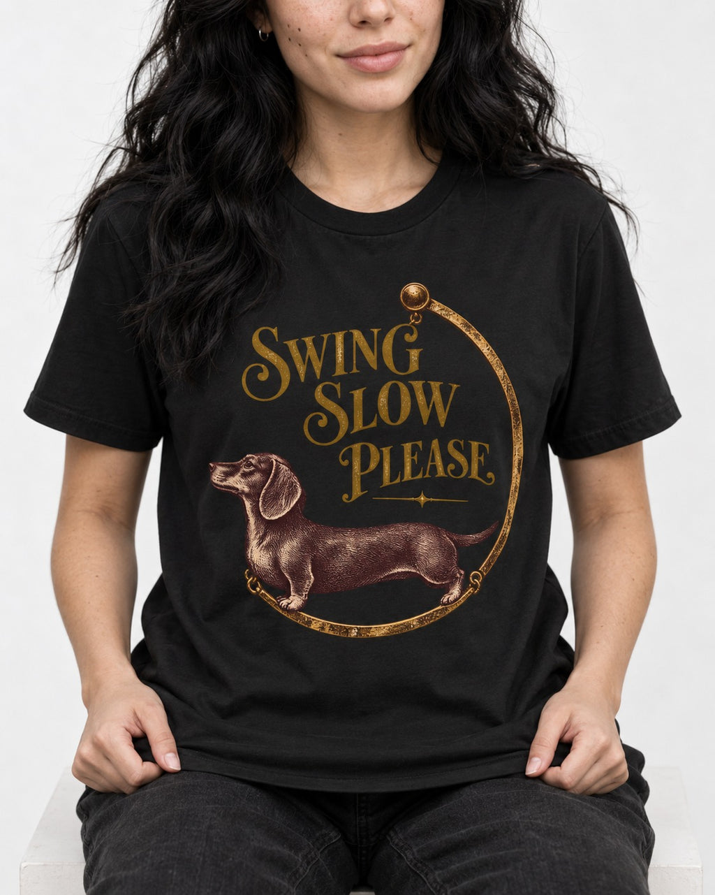 Dachshund Swing Slow Please Necklace Frame Graphic T-Shirt in Black, worn by a seated model