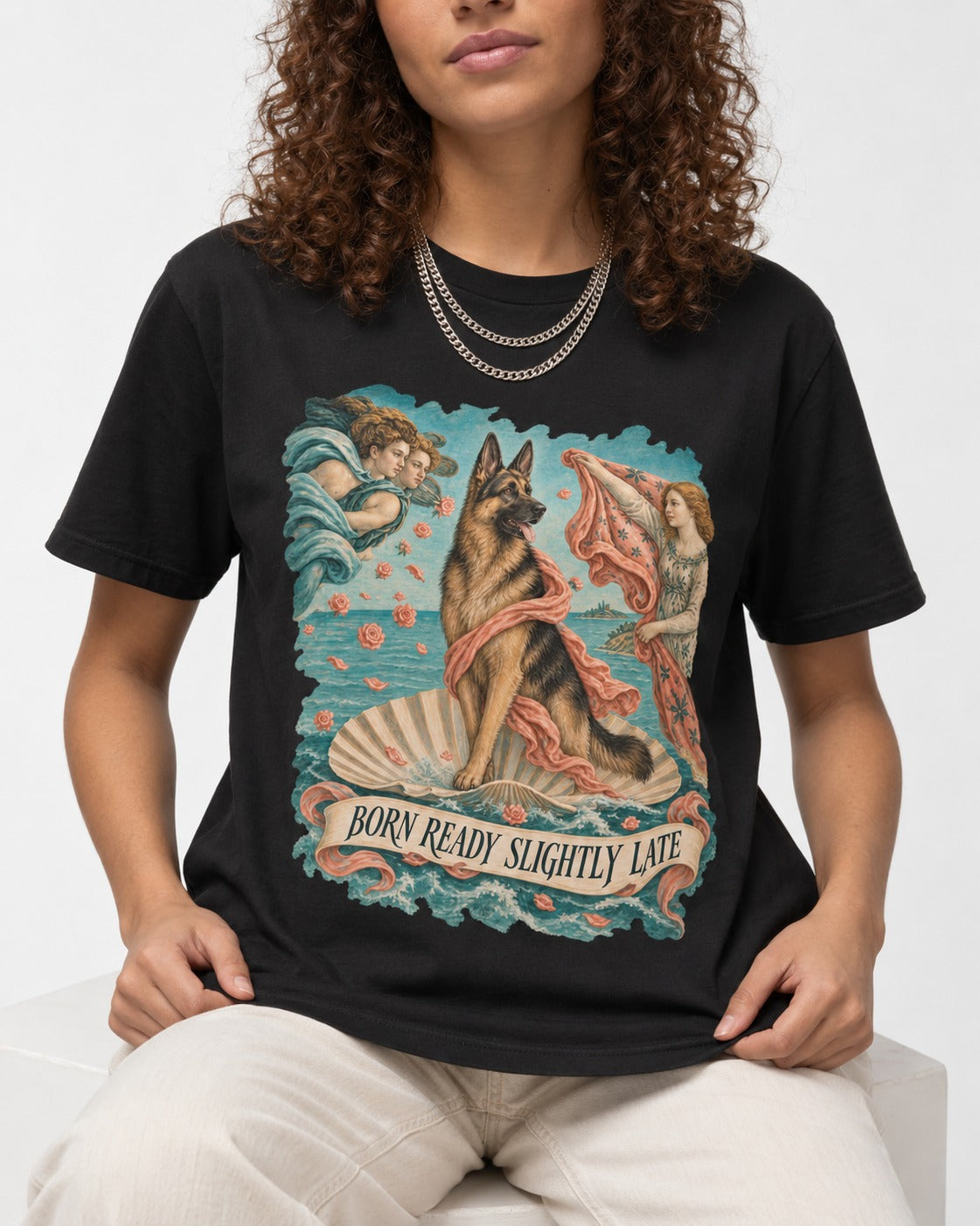 German Shepherd Dog Born Ready Slightly Late Venus Graphic T-Shirt in Black, worn by a seated model
