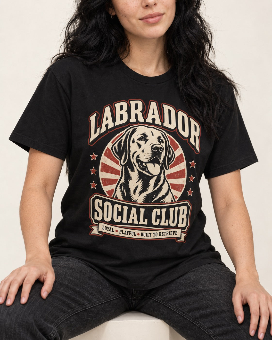 Labrador Retriever Social Club Loyal Playful Built to Retrieve Badge Graphic T-Shirt in Black, worn by a seated model