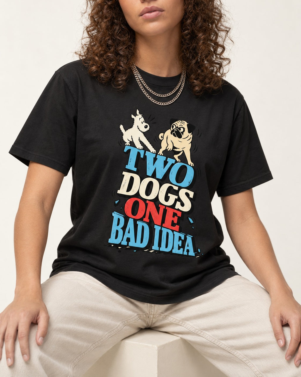 Pug Two Dogs One Bad Idea Graphic T-Shirt in Black, worn by a seated model