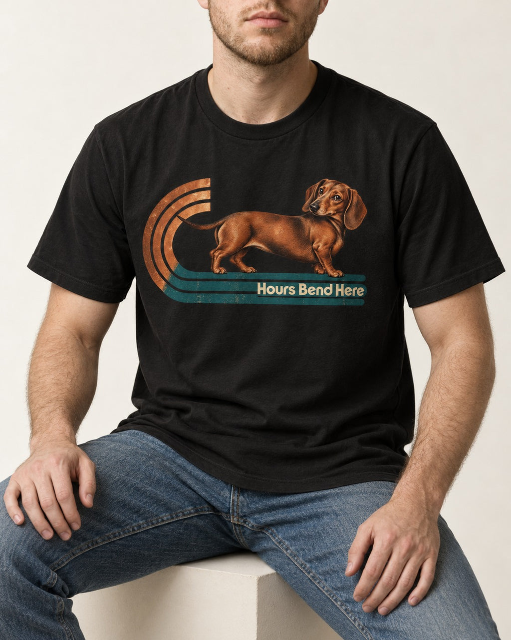 Dachshund Hours Bend Here Retro Track Graphic T-Shirt in Black, worn by a seated model