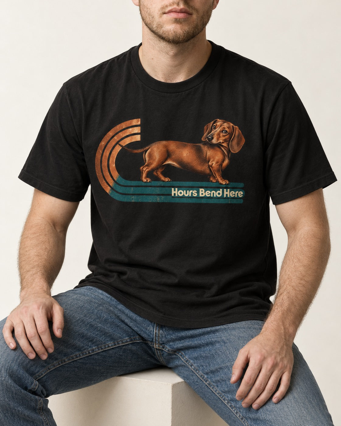 Dachshund Hours Bend Here Retro Track Graphic T-Shirt in Black, worn by a seated model