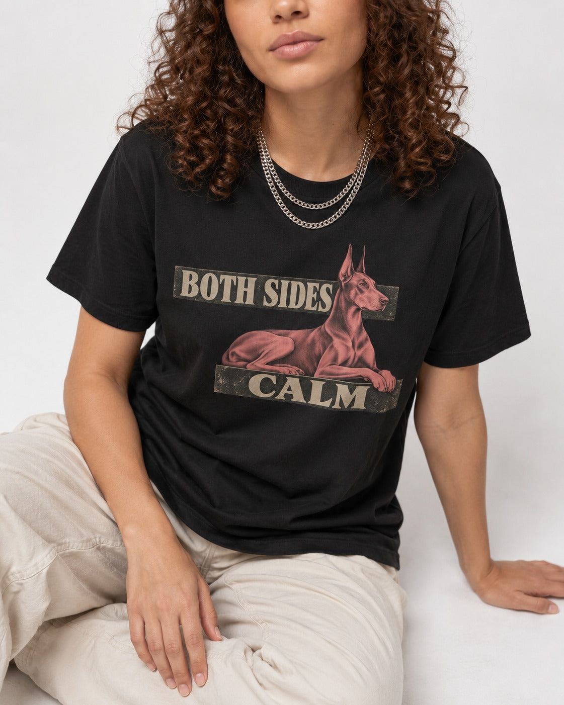 Doberman Both Sides Calm Banner T-Shirt in Black, worn by a seated model