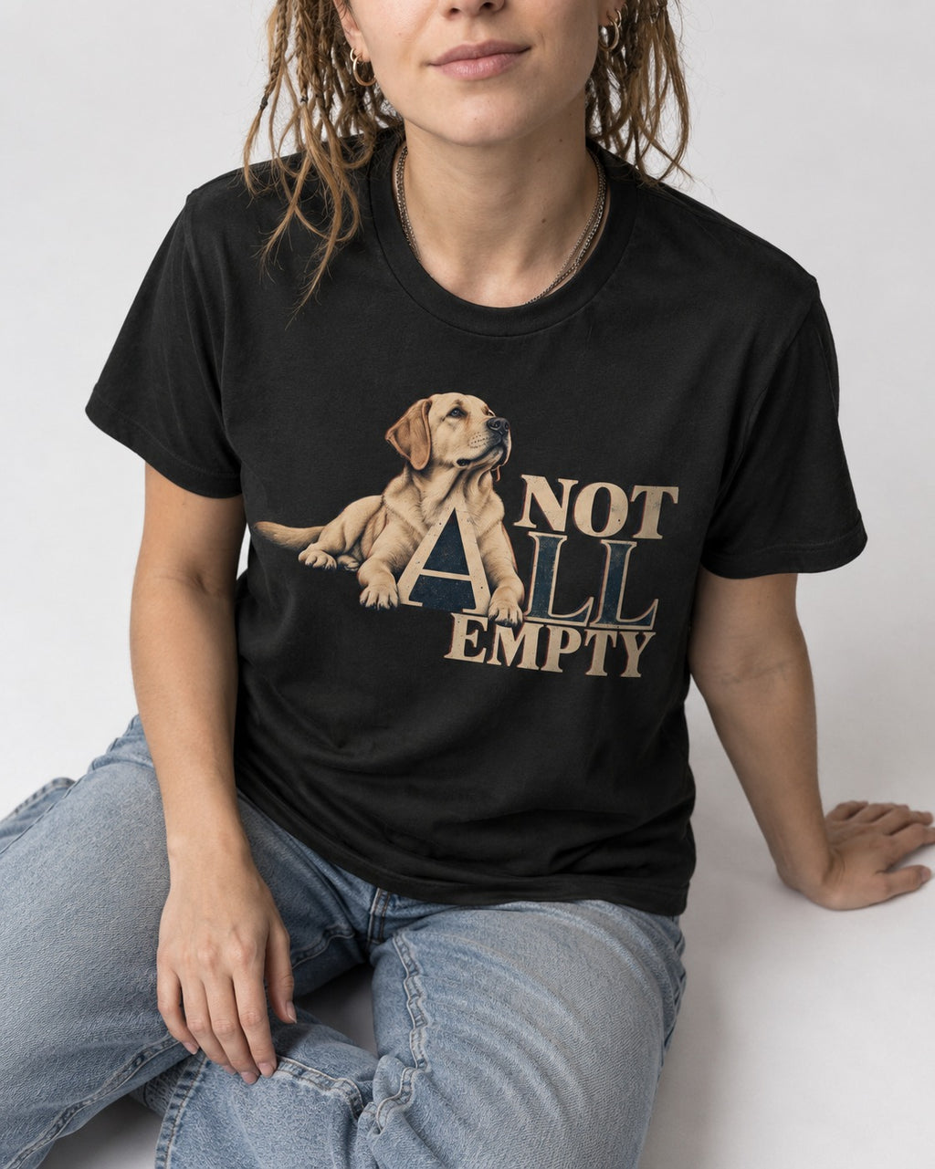 Labrador Retriever Not All Empty Lounging Typography Graphic T-Shirt in Black, worn by a seated model