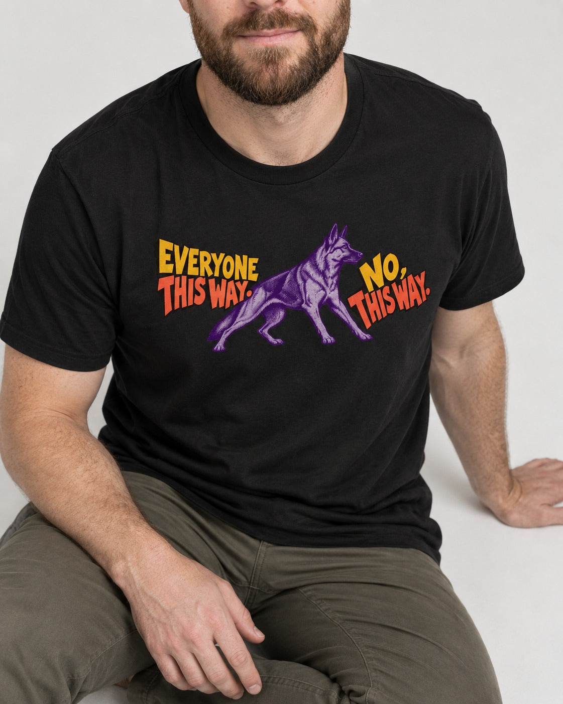 German Shepherd Dog Everyone This Way No This Way Direction Graphic T-Shirt in Black, worn by a seated model