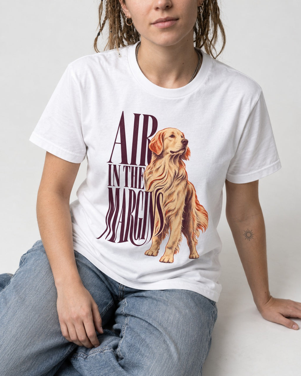 Golden Retriever In the Margins T-Shirt in White, worn by a seated model